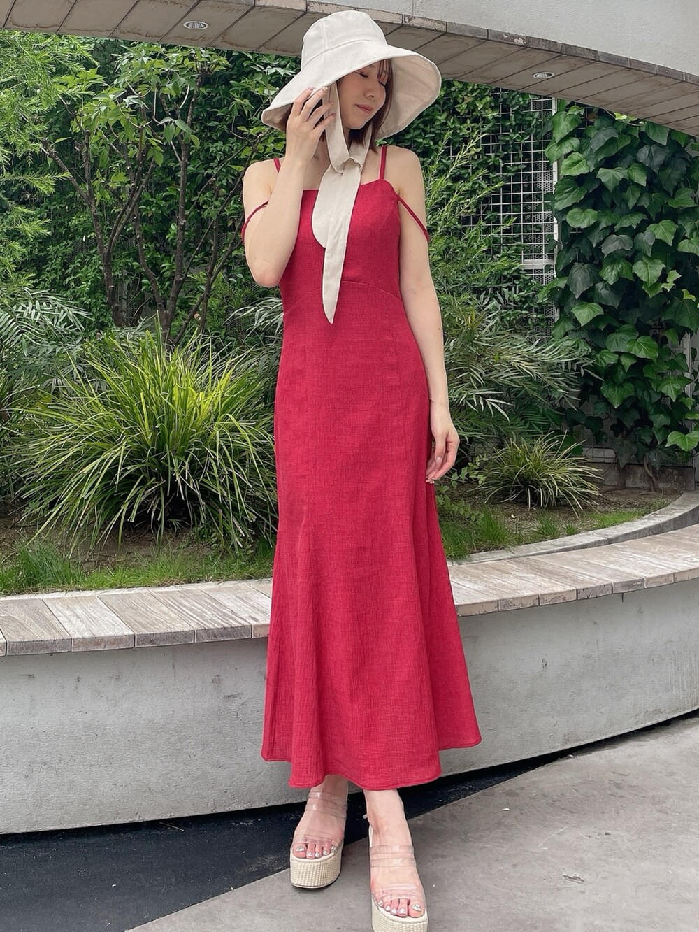 レッド系のワンピース、ホワイト系のサンダル、ホワイト系のハットを着用したレディースの夏コーディネートの2枚目の写真