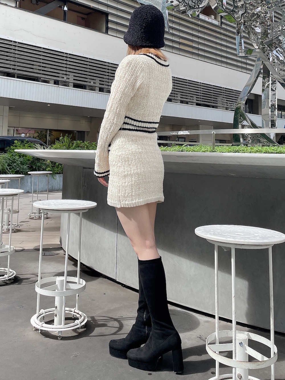 ホワイト系のカーディガン/ボレロ、ホワイト系のスカート、ブラック系のブーツを着用したレディースの秋コーディネートの2枚目の写真