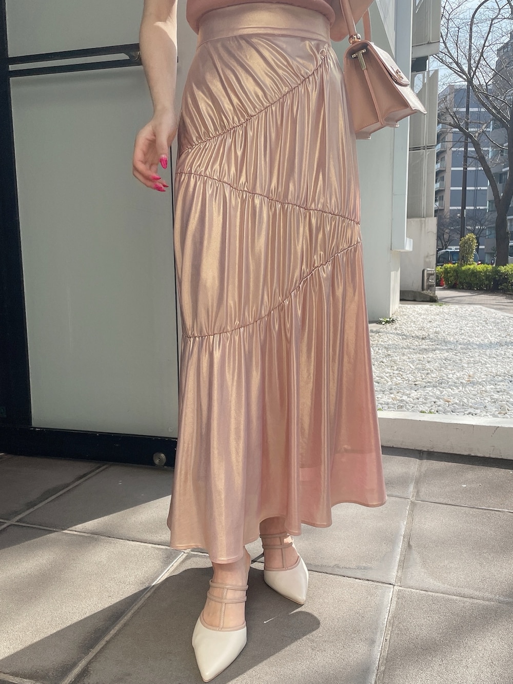 オレンジ系のニット/セーター、ゴールド系のスカート、ピンク系のハンドバッグを着用したレディースの春コーディネートの5枚目の写真