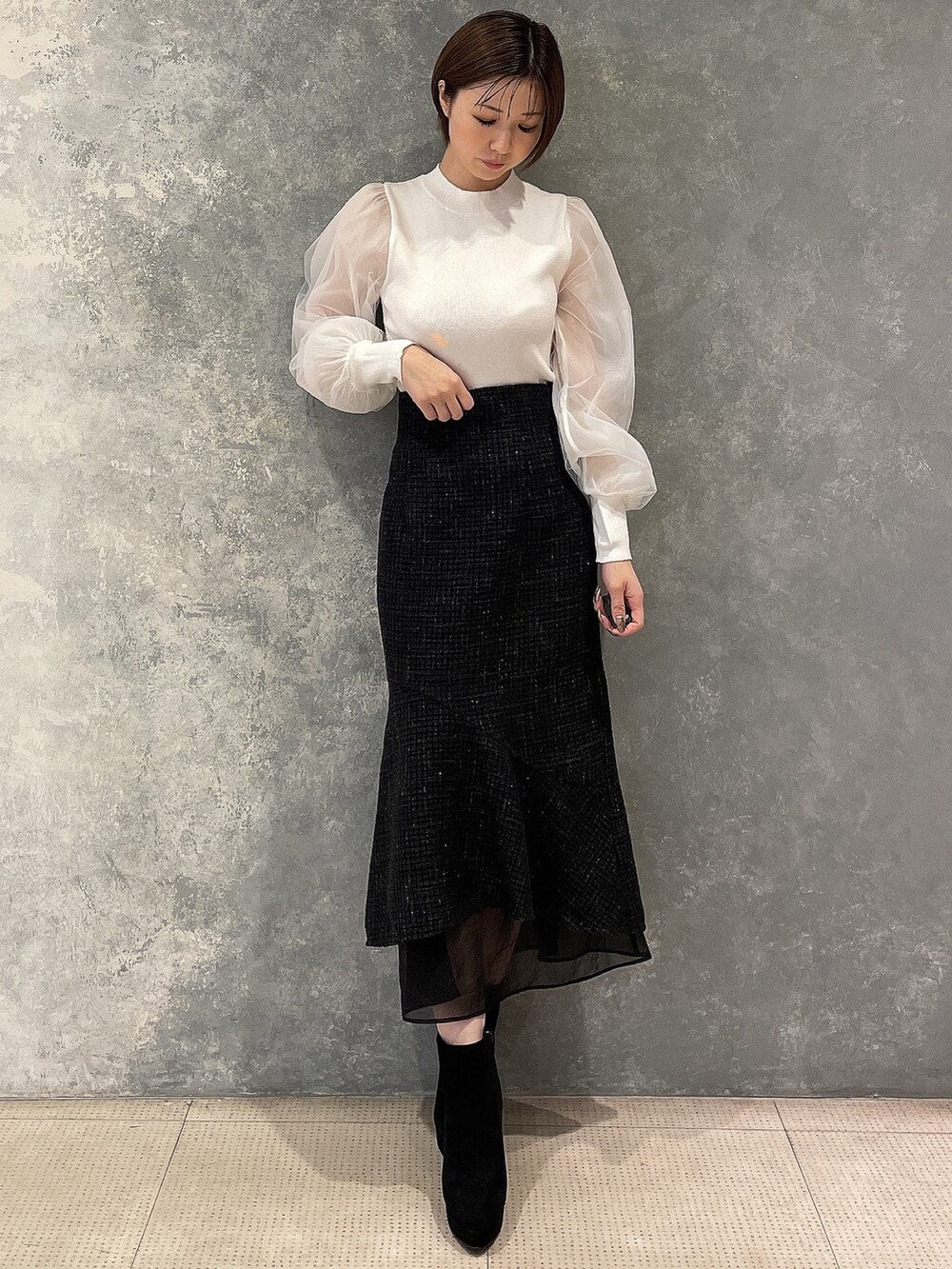 ホワイト系のダウンジャケット/コート、ブラック系のスカート、ブラック系のブーツを着用したレディースの秋コーディネートの6枚目の写真