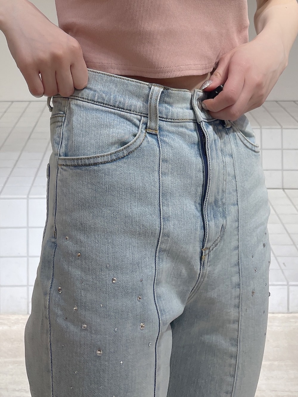 ピンク系のパーカー、ブルー系のデニムパンツ、ホワイト系のサンダルを着用したレディースの春コーディネートの4枚目の写真