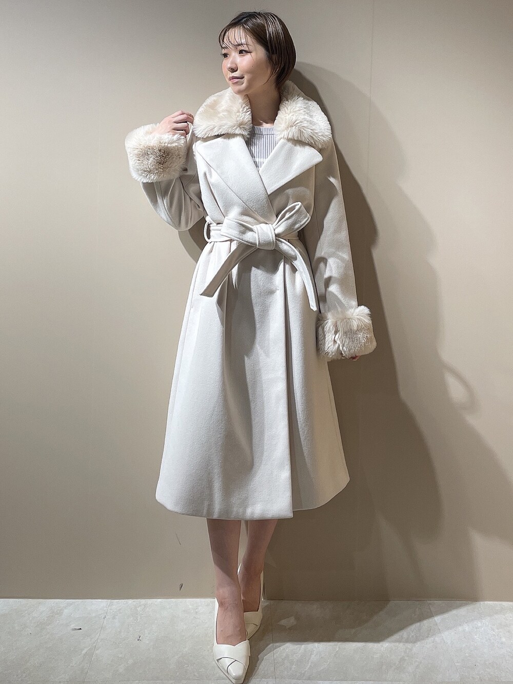 グレー系のワンピース、ホワイト系のパンプス、ホワイト系のチェスターコートを着用したレディースの秋コーディネートの3枚目の写真
