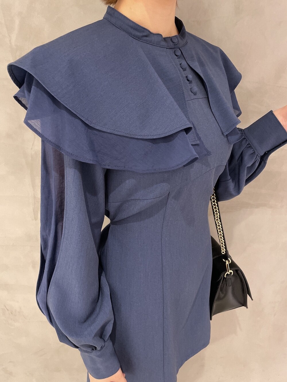 ブラック系のハンドバッグ、ブラック系のブーツ、ブルー系のワンピースを着用したレディースの冬コーディネートの7枚目の写真