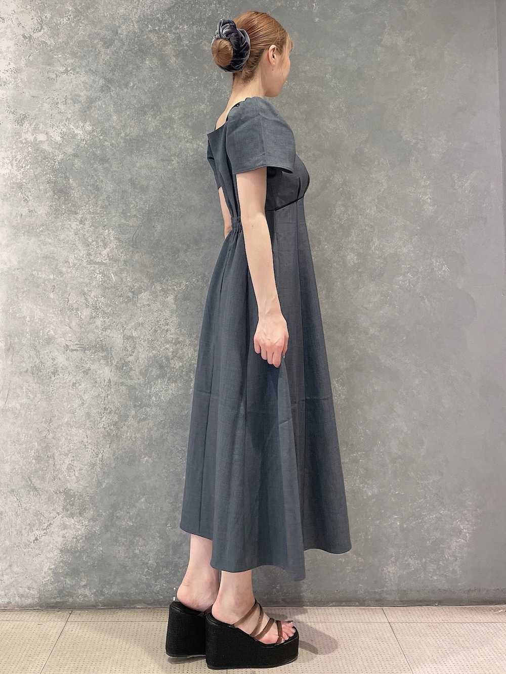 グレー系のワンピース、ブラック系のサンダル、グレー系のシュシュを着用したレディースの夏コーディネートの5枚目の写真