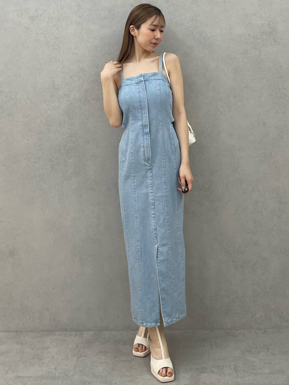 ブルー系のデニムジャケット、ブルー系のワンピース、ホワイト系のハンドバッグを着用したレディースの春コーディネートの4枚目の写真