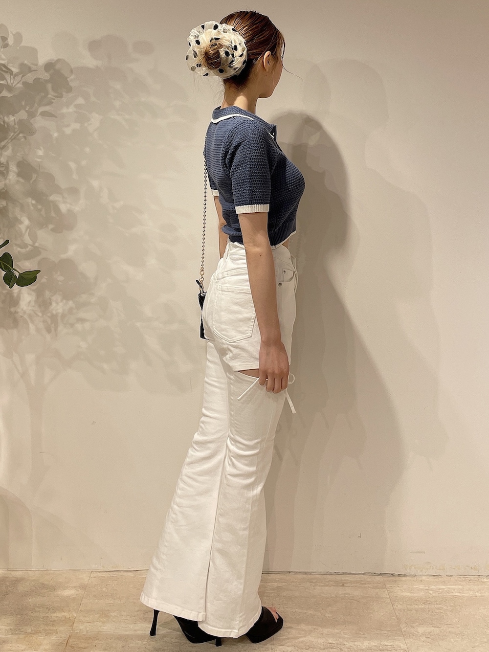 ブルー系のニット/セーター、ホワイト系のデニムパンツ、ブラック系のハンドバッグを着用したレディースの春コーディネートの3枚目の写真