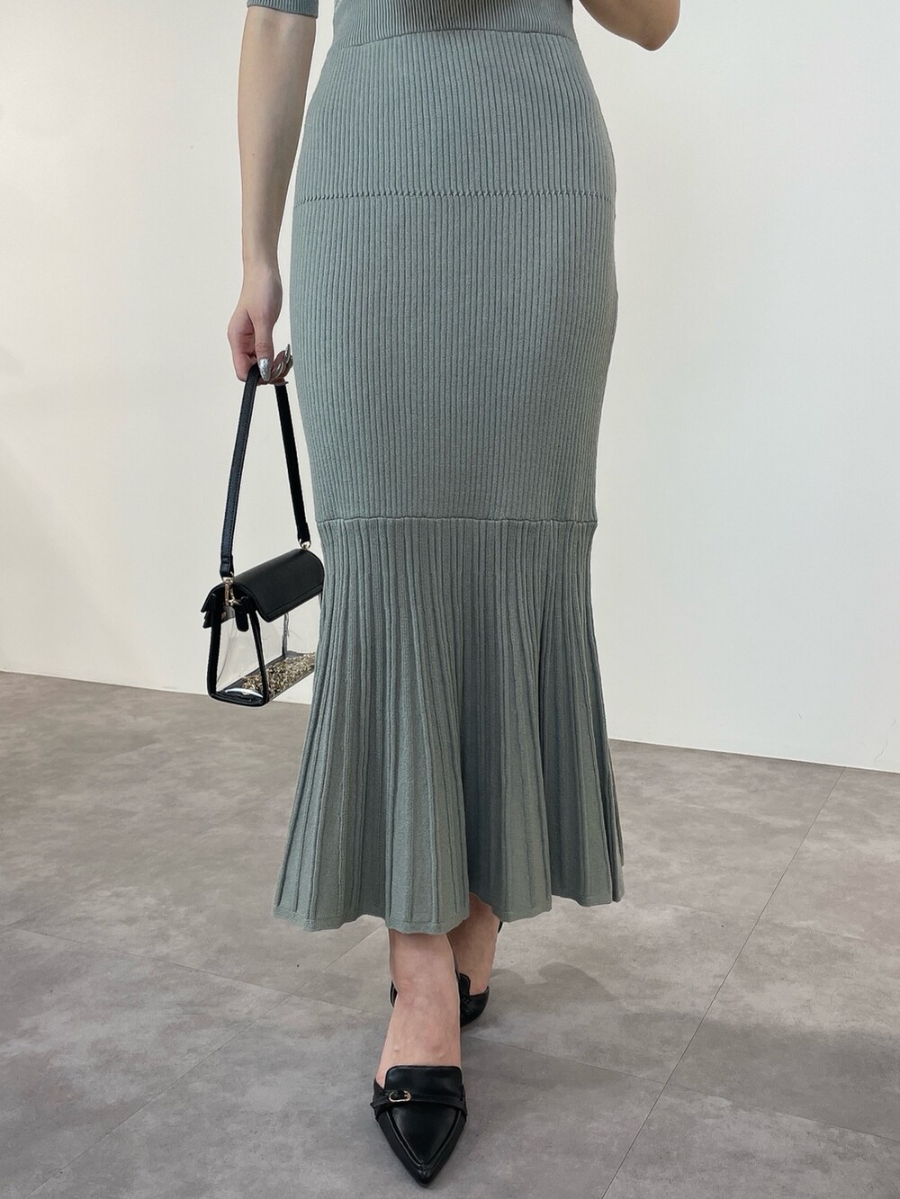 グリーン系のワンピース、ブラック系のパンプス、ブラック系のハンドバッグを着用したレディースの冬コーディネートの7枚目の写真