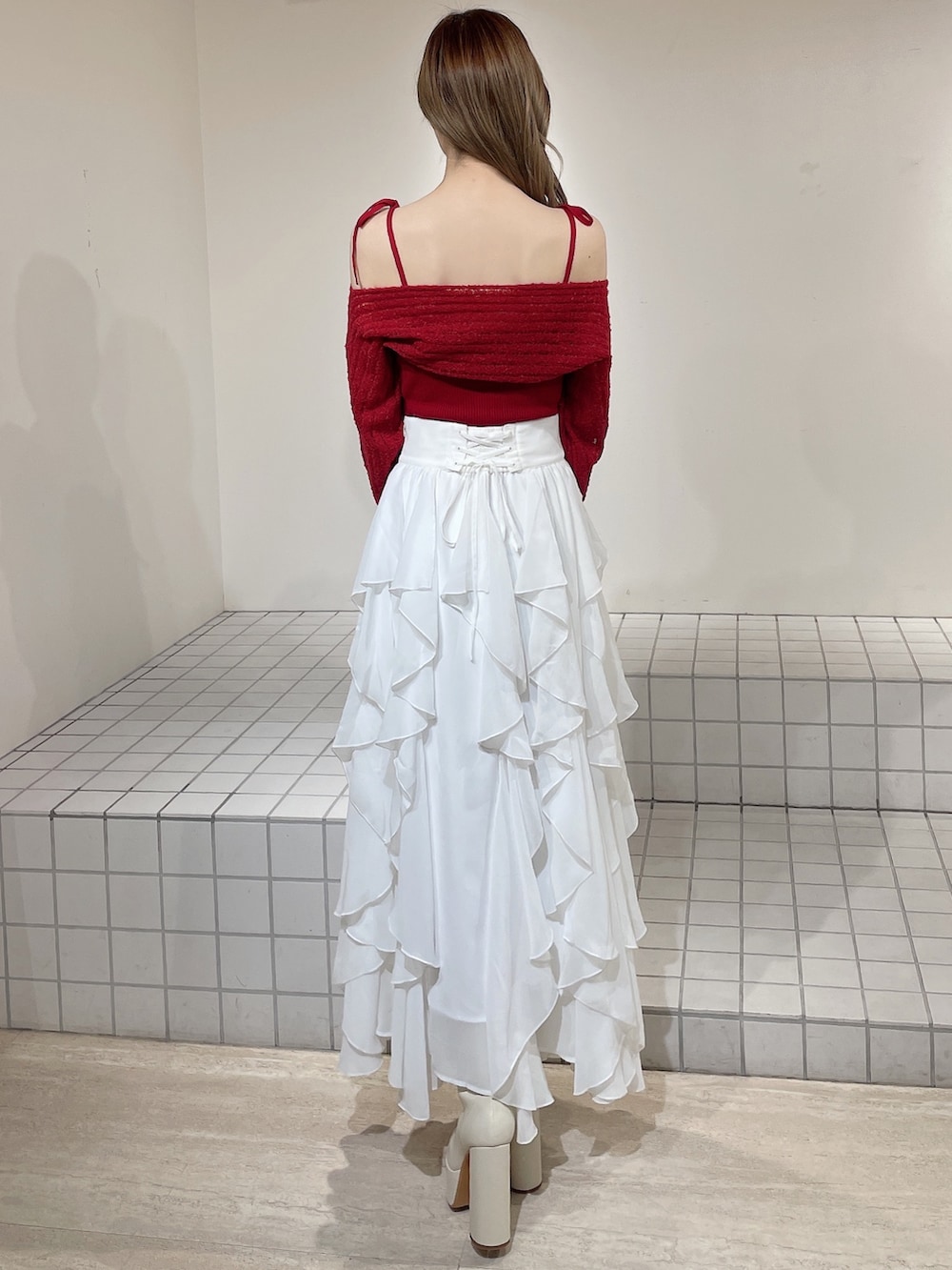 ブルー系のテーラードジャケット、レッド系のニット/セーター、ホワイト系のスカートを着用したレディースの冬コーディネートの7枚目の写真