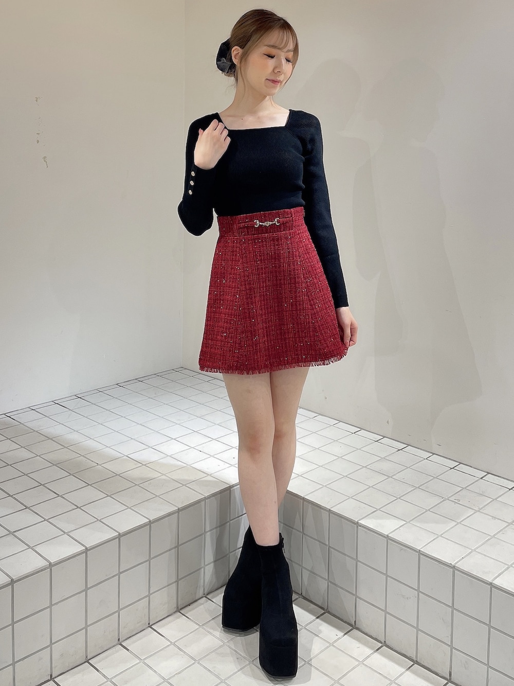 レッド系のテーラードジャケット、レッド系のスカート、ブラック系のニット/セーターを着用したレディースの秋コーディネートの5枚目の写真