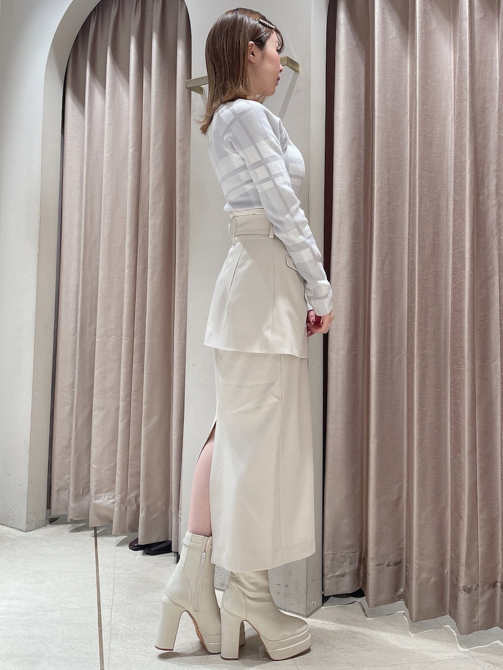 グレー系のニット/セーター、ホワイト系のスカート、ホワイト系のブーツを着用したレディースの冬コーディネートの3枚目の写真