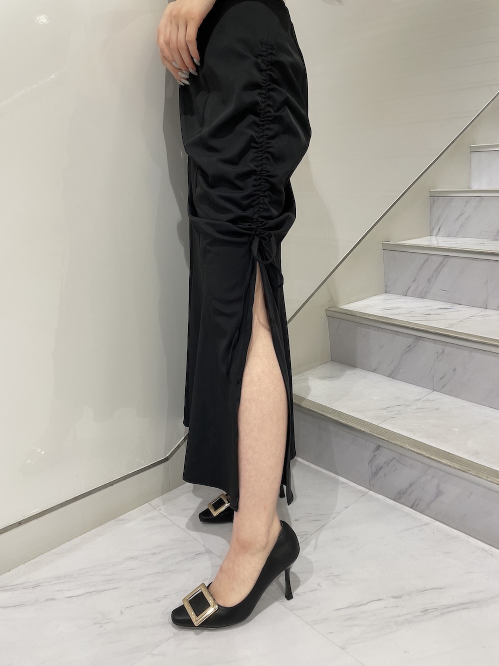 ホワイト系のニット/セーター、ブラック系のスカート、ブラック系のパンプスを着用したレディースの春コーディネートの6枚目の写真