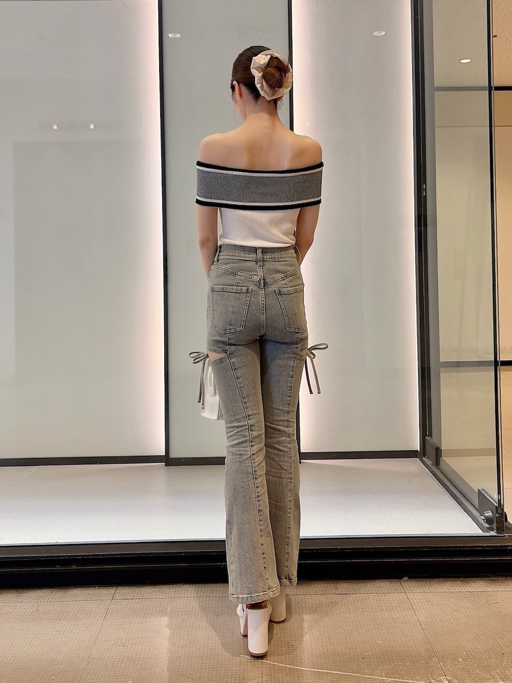 ホワイト系のニット/セーター、ブルー系のデニムパンツ、ホワイト系のハンドバッグを着用したレディースの夏コーディネートの4枚目の写真