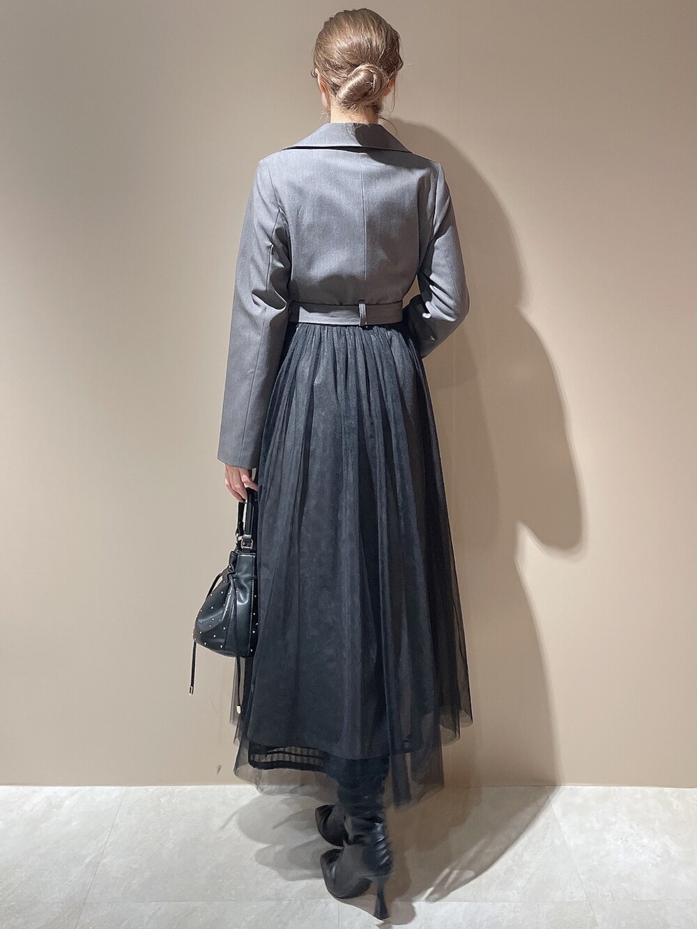 グレー系のトレンチコート、ブラック系のハンドバッグ、ブラック系のブーツを着用したレディースの秋コーディネートの6枚目の写真