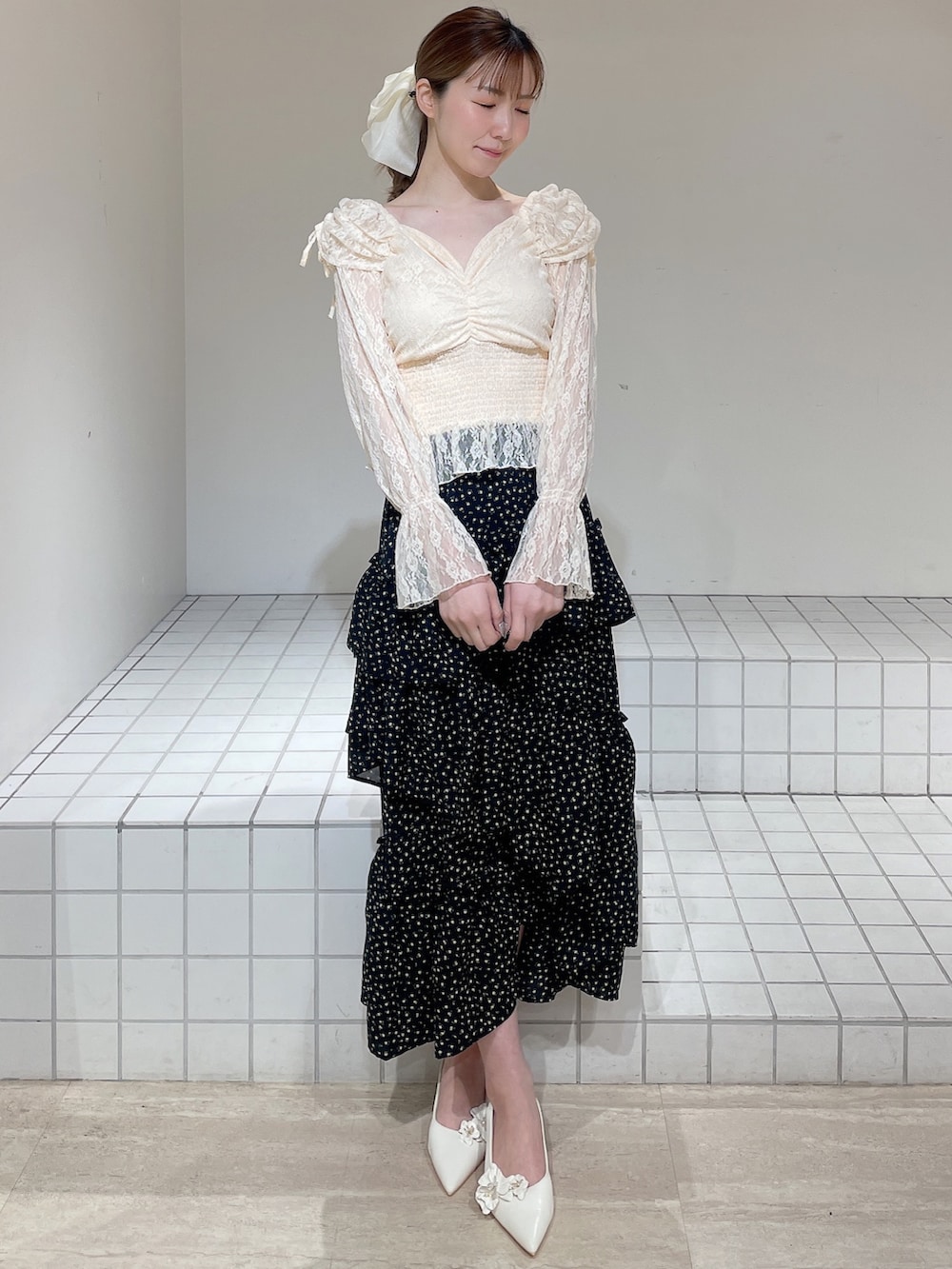 オレンジ系のシャツ/ブラウス、ブラック系のスカート、ホワイト系のパンプスを着用したレディースの春コーディネートの2枚目の写真