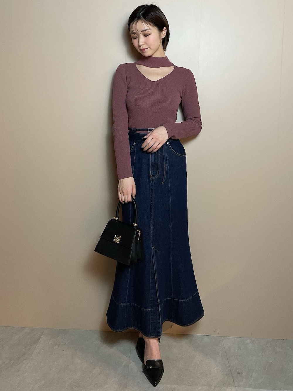 ピンク系のニット/セーター、ブルー系のデニムスカート、ブラック系のパンプスを着用したレディースの冬コーディネートの2枚目の写真