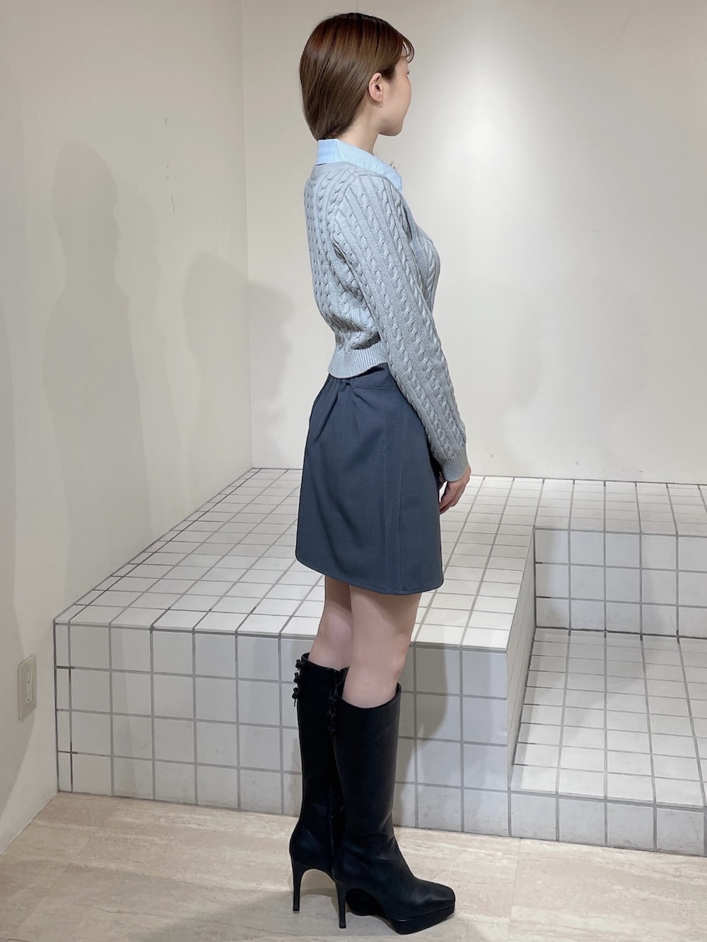 グレー系のニット/セーター、グレー系のスカート、ブラック系のブーツを着用したレディースの冬コーディネートの3枚目の写真