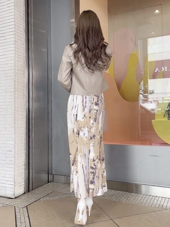 ベージュ系のライダースジャケット、パープル系のスカート、ホワイト系のパンプスを着用したレディースの冬コーディネートの2枚目の写真