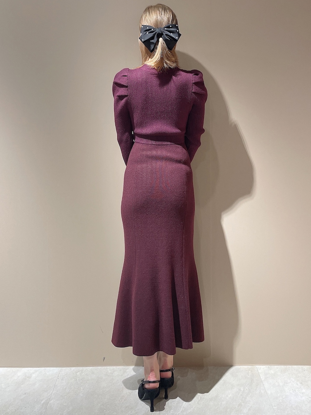 レッド系のワンピース、ブラック系のパンプス、ブラック系のダウンジャケット/コートを着用したレディースの秋コーディネートの4枚目の写真