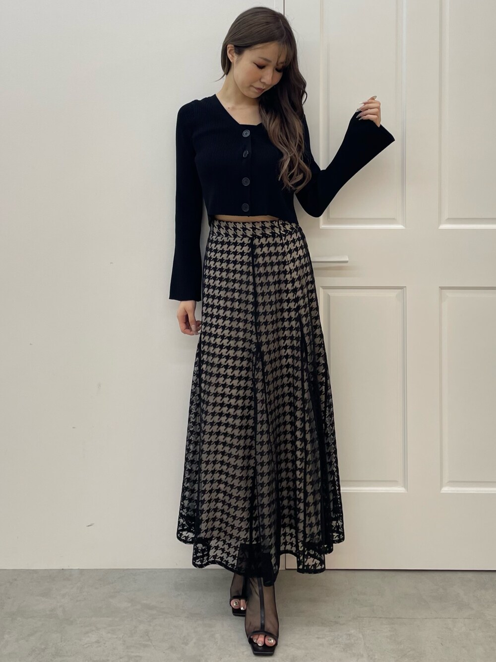 ブラック系のニット/セーター、ブラック系のスカート、ブラック系のブーツを着用したレディースの秋コーディネートの2枚目の写真