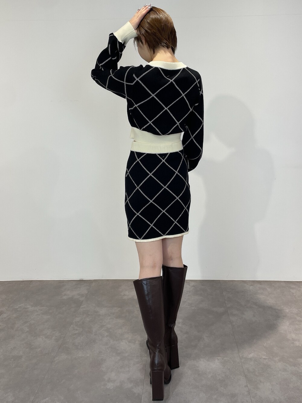 ブラック系のカーディガン/ボレロ、ブラック系のスカート、ブラウン系のブーツを着用したレディースの冬コーディネートの4枚目の写真