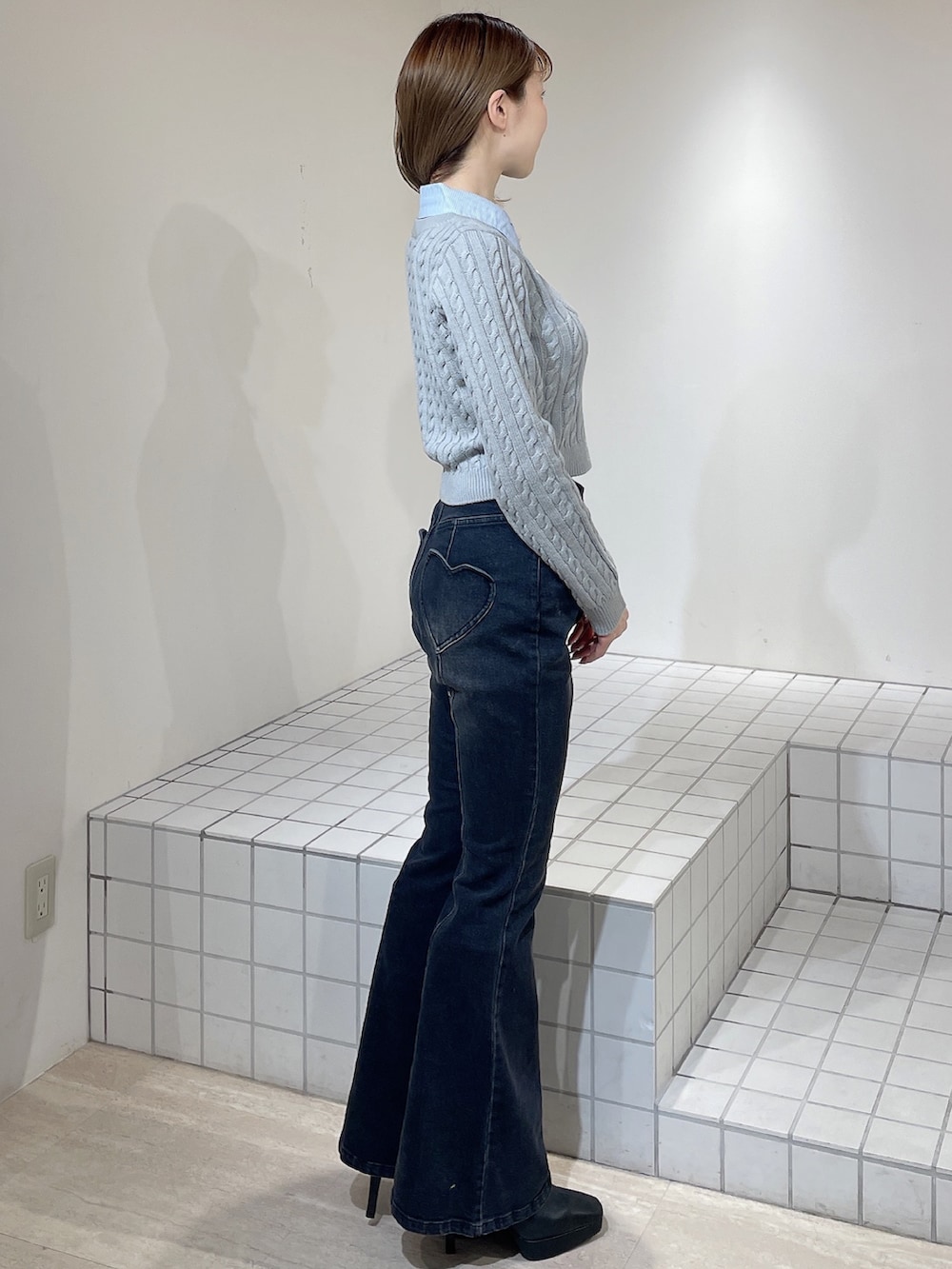 グレー系のニット/セーター、ブラック系のデニムパンツ、ブラック系のブーツを着用したレディースの冬コーディネートの2枚目の写真