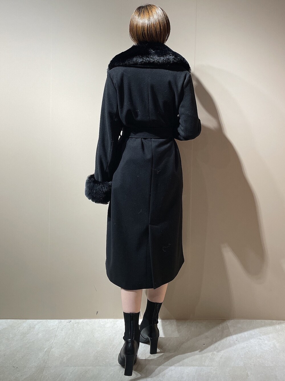 ブラック系のチェスターコート、ブラック系のブーツを着用したレディースの秋コーディネートの3枚目の写真