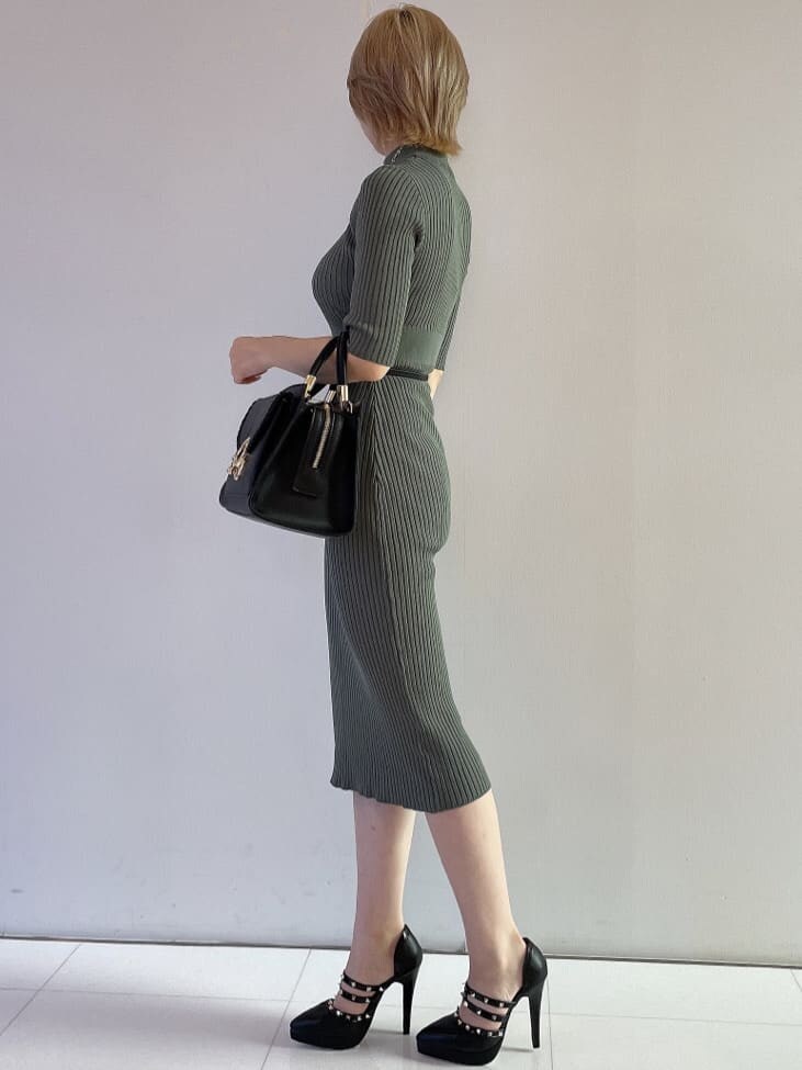 ブラック系のハンドバッグ、グリーン系のワンピース、ブラック系のパンプスを着用したレディースの夏コーディネートの3枚目の写真