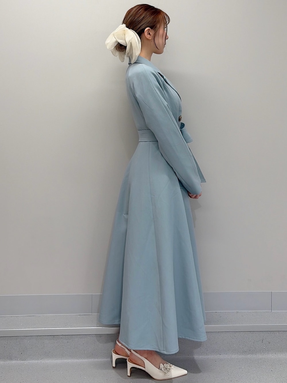 ブルー系のトレンチコート、ホワイト系のパンプス、ホワイト系のバレッタ/ヘアクリップを着用したレディースの冬コーディネートの5枚目の写真