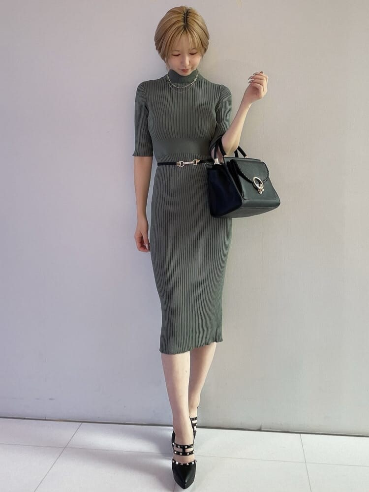 ブラック系のハンドバッグ、グリーン系のワンピース、ブラック系のパンプスを着用したレディースの夏コーディネートの2枚目の写真