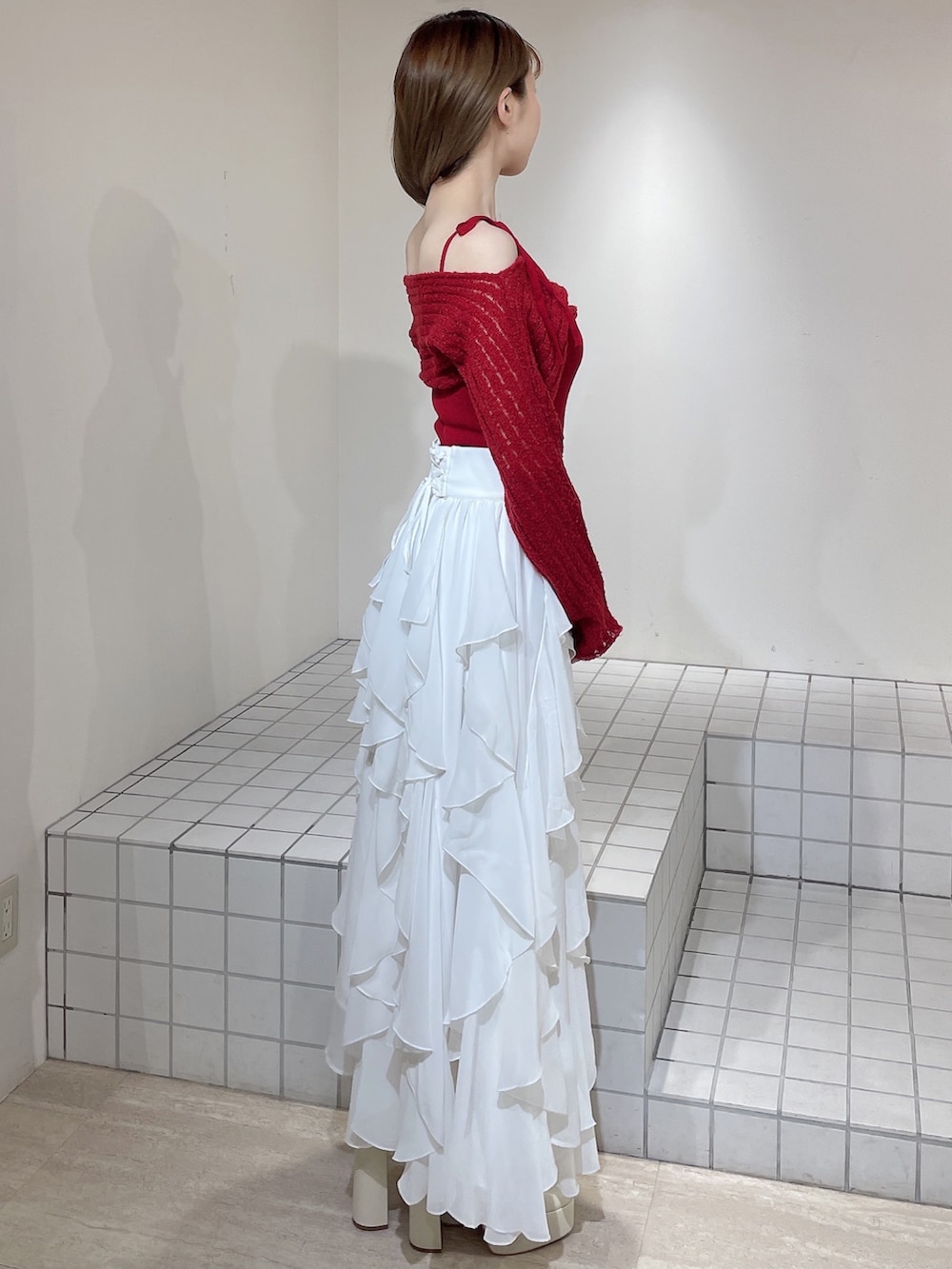 ブルー系のテーラードジャケット、レッド系のニット/セーター、ホワイト系のスカートを着用したレディースの冬コーディネートの6枚目の写真