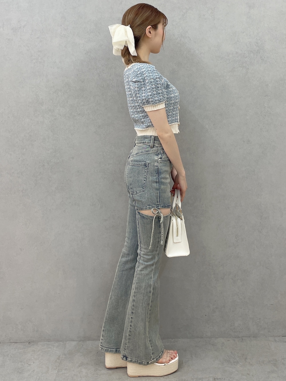 ブルー系のニット/セーター、ホワイト系のハンドバッグ、ホワイト系のサンダルを着用したレディースの春コーディネートの2枚目の写真