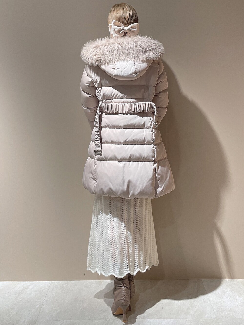 ベージュ系のブーツ、ベージュ系のダウンジャケット/コート、ホワイト系のワンピースを着用したレディースの秋コーディネートの3枚目の写真