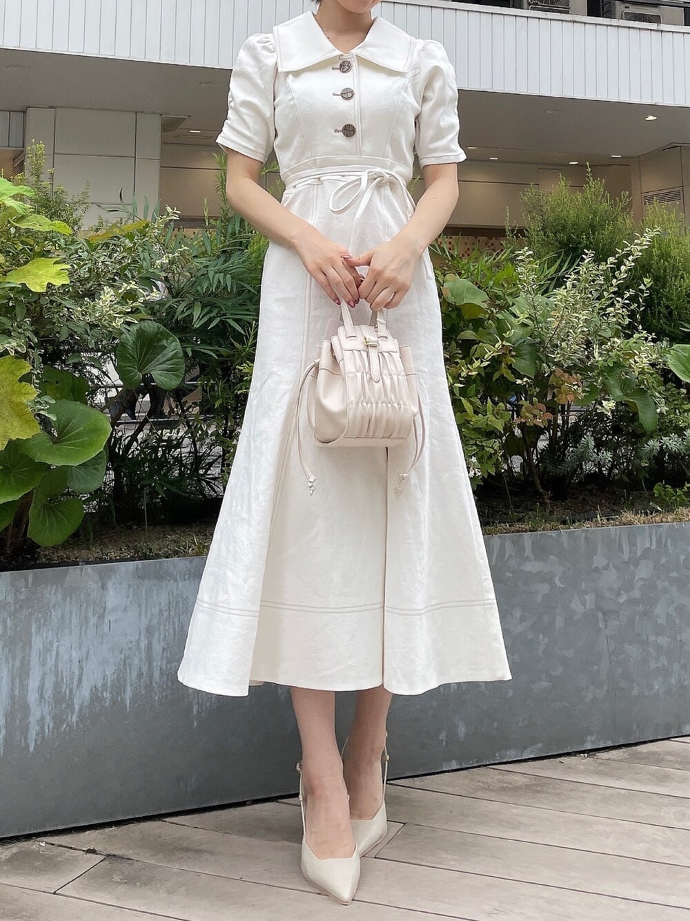 ホワイト系のワンピース、ホワイト系のハンドバッグ、ベージュ系のサンダルを着用したレディースの夏コーディネートの2枚目の写真