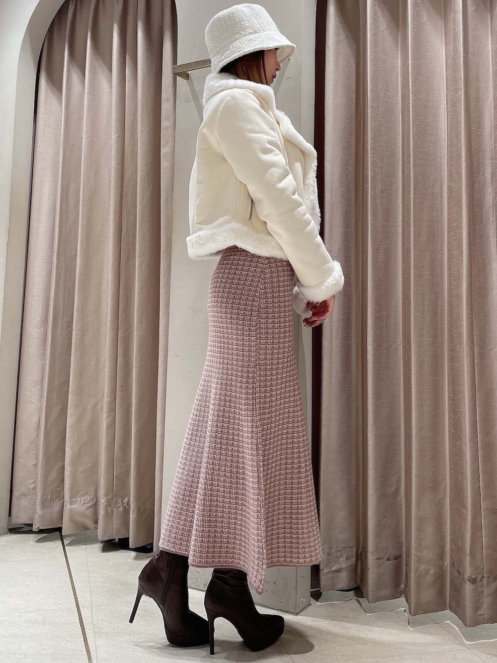 ピンク系のワンピース、ブラウン系のブーツ、ホワイト系のハットを着用したレディースの冬コーディネートの5枚目の写真