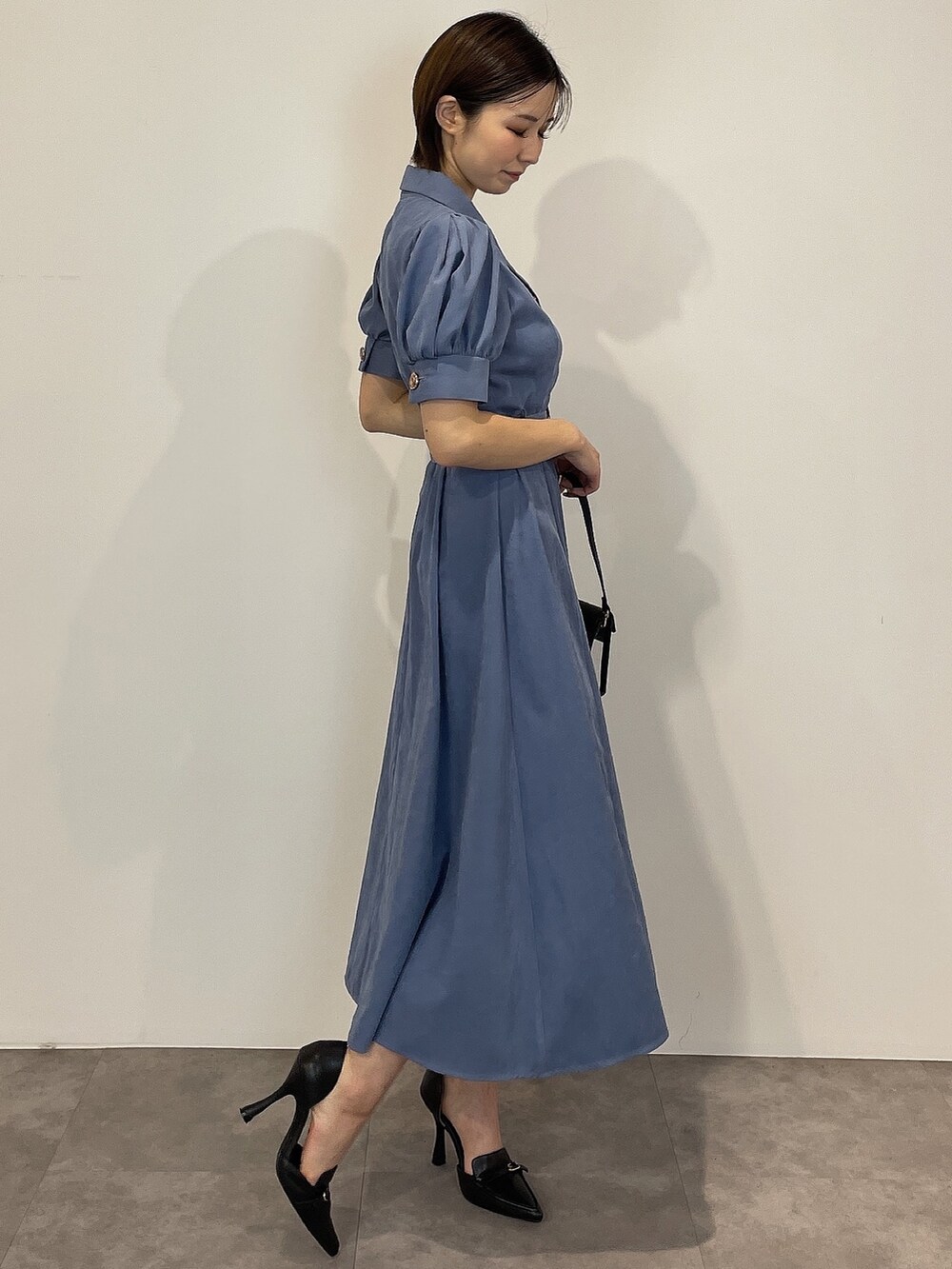 ブルー系のワンピース、ブラック系のパンプス、ブラック系のハンドバッグを着用したレディースの冬コーディネートの5枚目の写真