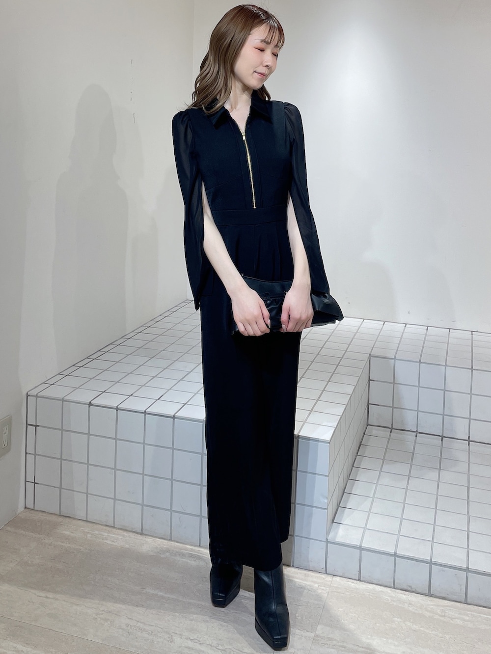 ブラック系のワンピース、ブラック系のブーツ、ブラック系のハンドバッグを着用したレディースの冬コーディネートの2枚目の写真