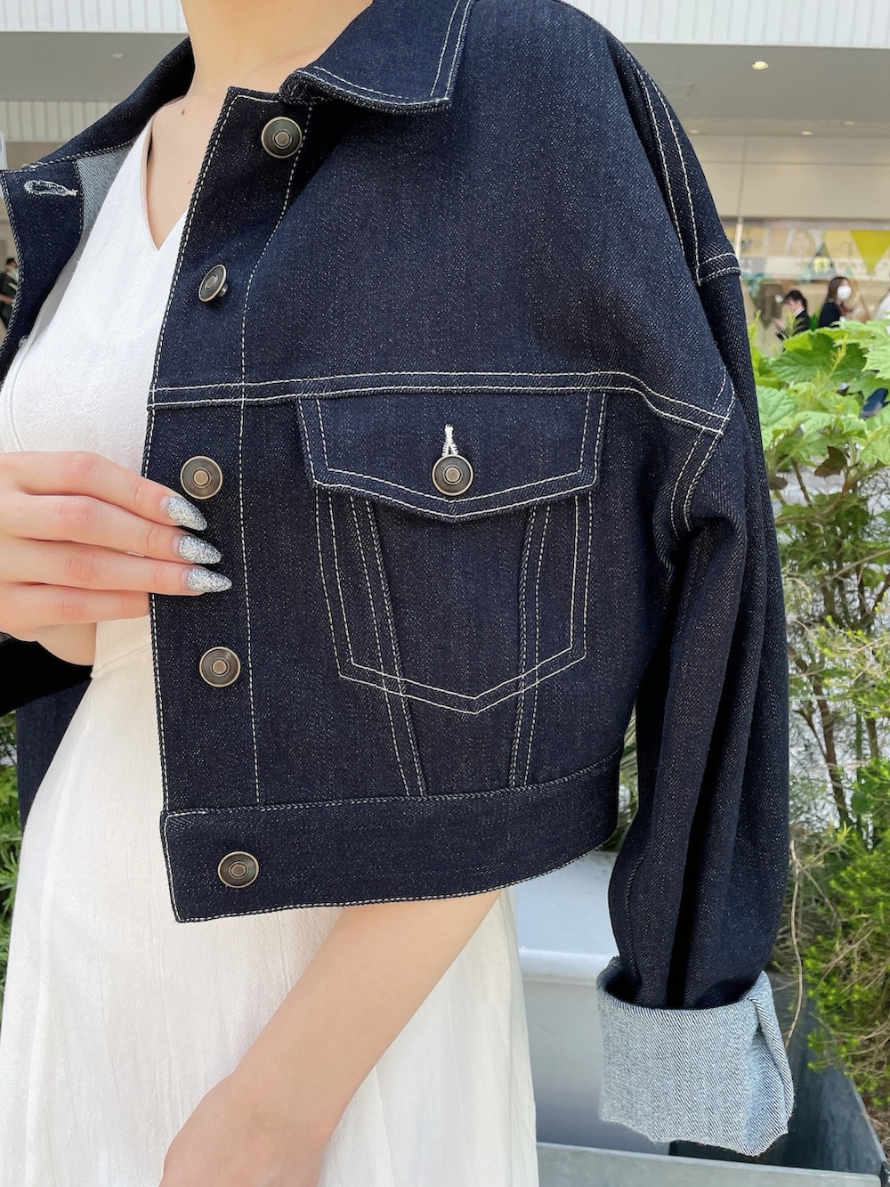 ホワイト系のワンピース、ブルー系のデニムジャケット、ゴールド系のサンダルを着用したレディースの春コーディネートの8枚目の写真