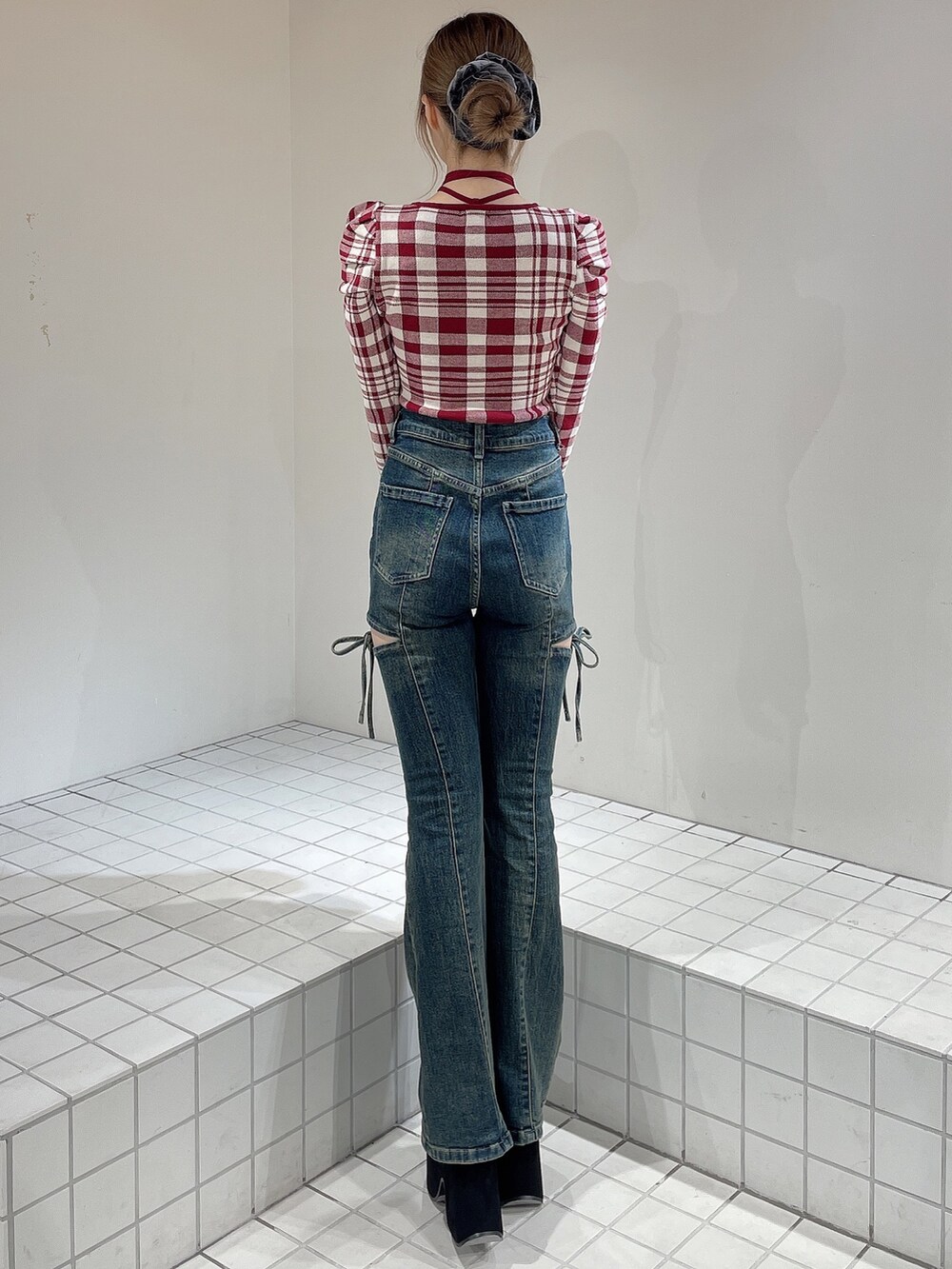 レッド系のニット/セーター、ブルー系のデニムパンツ、ブラック系のブーツを着用したレディースの秋コーディネートの4枚目の写真