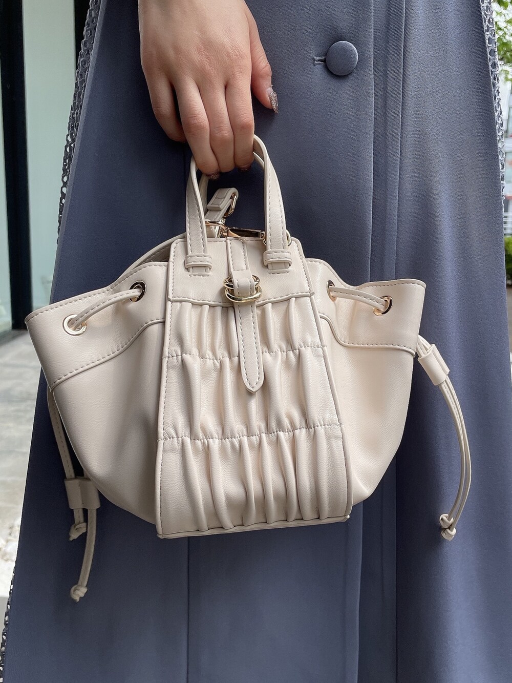 ホワイト系のハンドバッグ、ホワイト系のサンダル、ブルー系のシャツワンピースを着用したレディースの夏コーディネートの6枚目の写真