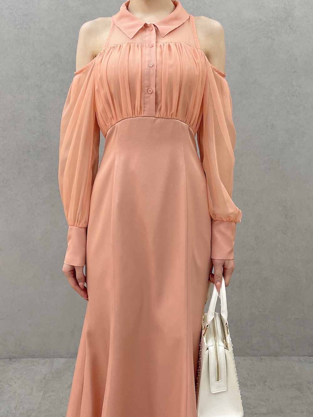 オレンジ系のワンピース、ホワイト系のハンドバッグ、ホワイト系のサンダルを着用したレディースの春コーディネートの5枚目の写真