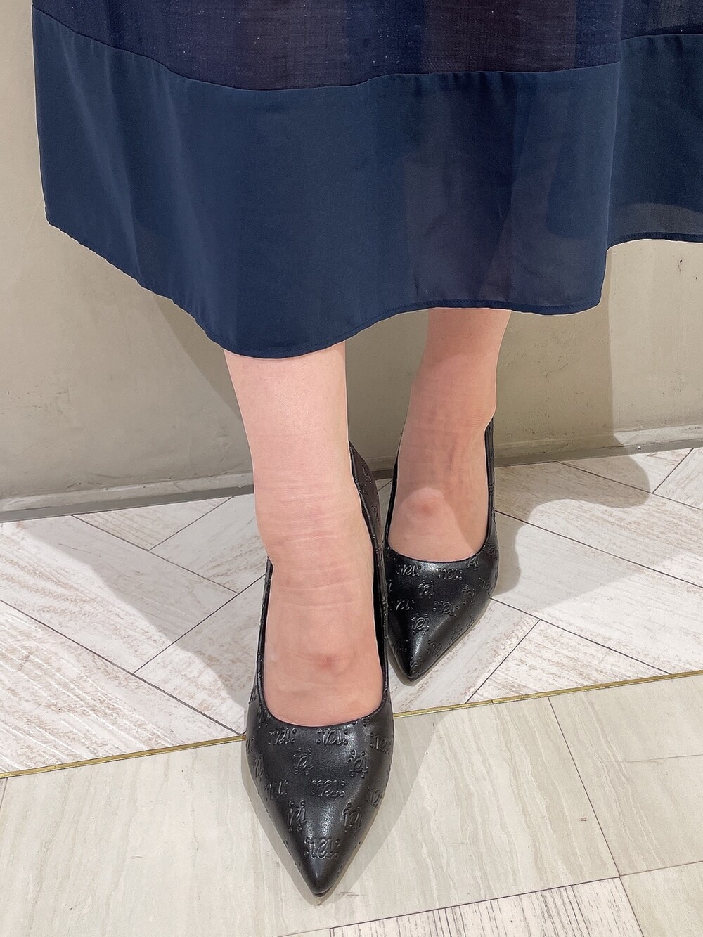 ブラック系のハンドバッグ、ブルー系のワンピース、ブラック系のパンプスを着用したレディースの冬コーディネートの8枚目の写真