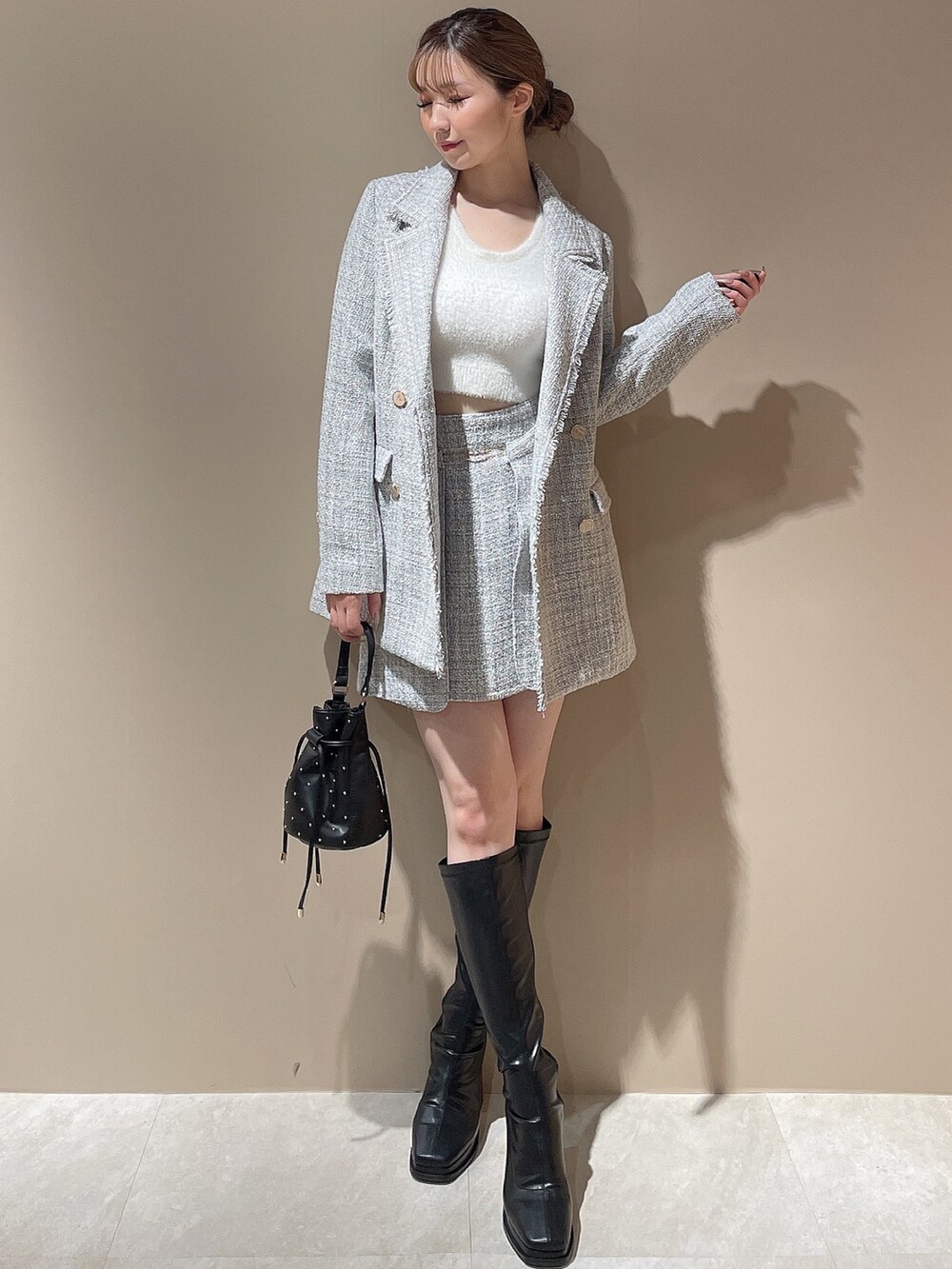 グレー系のテーラードジャケット、グレー系のスカート、ホワイト系のニット/セーターを着用したレディースの秋コーディネートの2枚目の写真