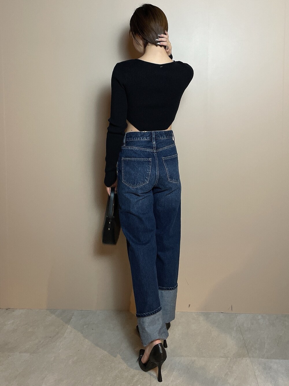 ブラック系のニット/セーター、ブルー系のデニムパンツ、ブラック系のハンドバッグを着用したレディースの冬コーディネートの5枚目の写真