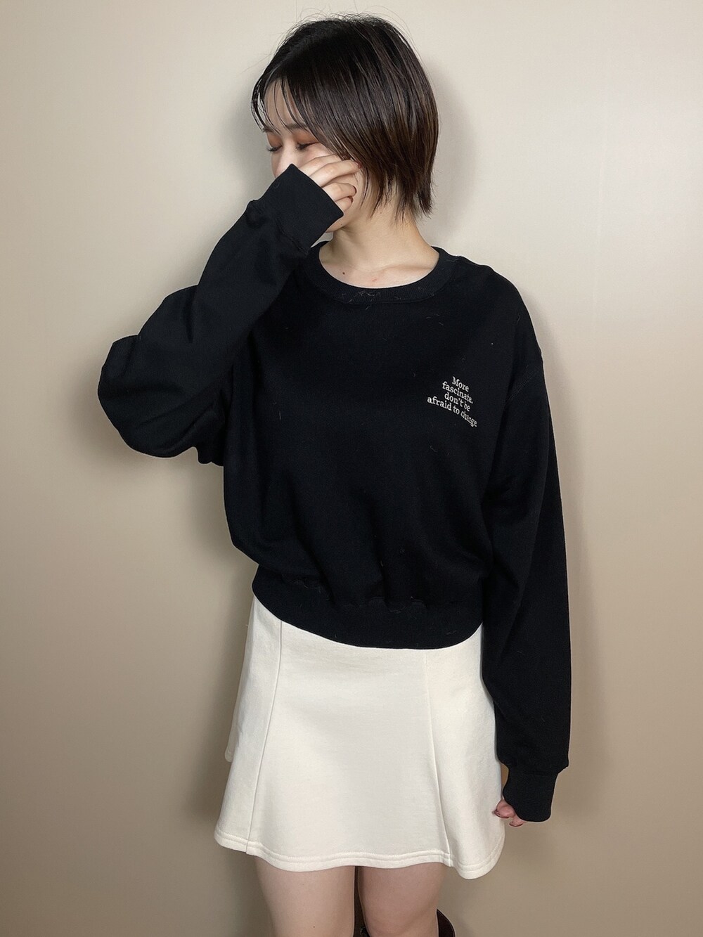 ホワイト系のスカート、ブラウン系のブーツ、ブラック系のスウェットを着用したレディースの夏コーディネートの5枚目の写真