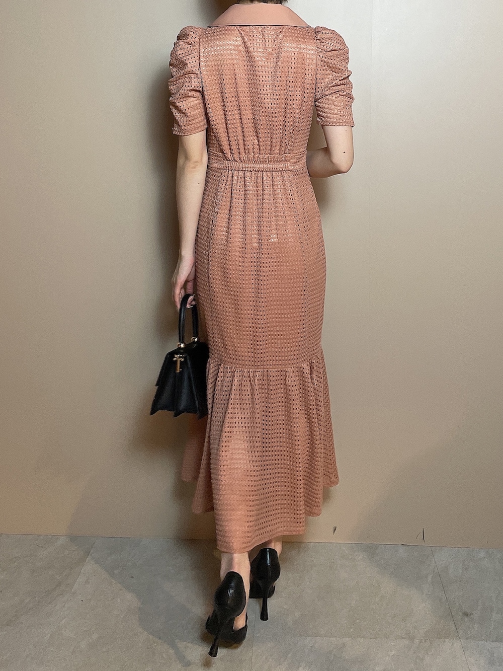 オレンジ系のワンピース、ブラック系のハンドバッグ、ブラック系のパンプスを着用したレディースの冬コーディネートの5枚目の写真