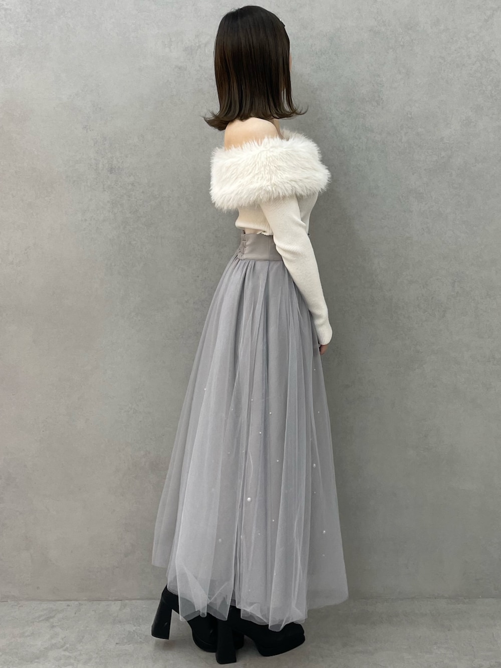 ホワイト系のニット/セーター、グレー系のスカート、ブラック系のブーツを着用したレディースの冬コーディネートの3枚目の写真