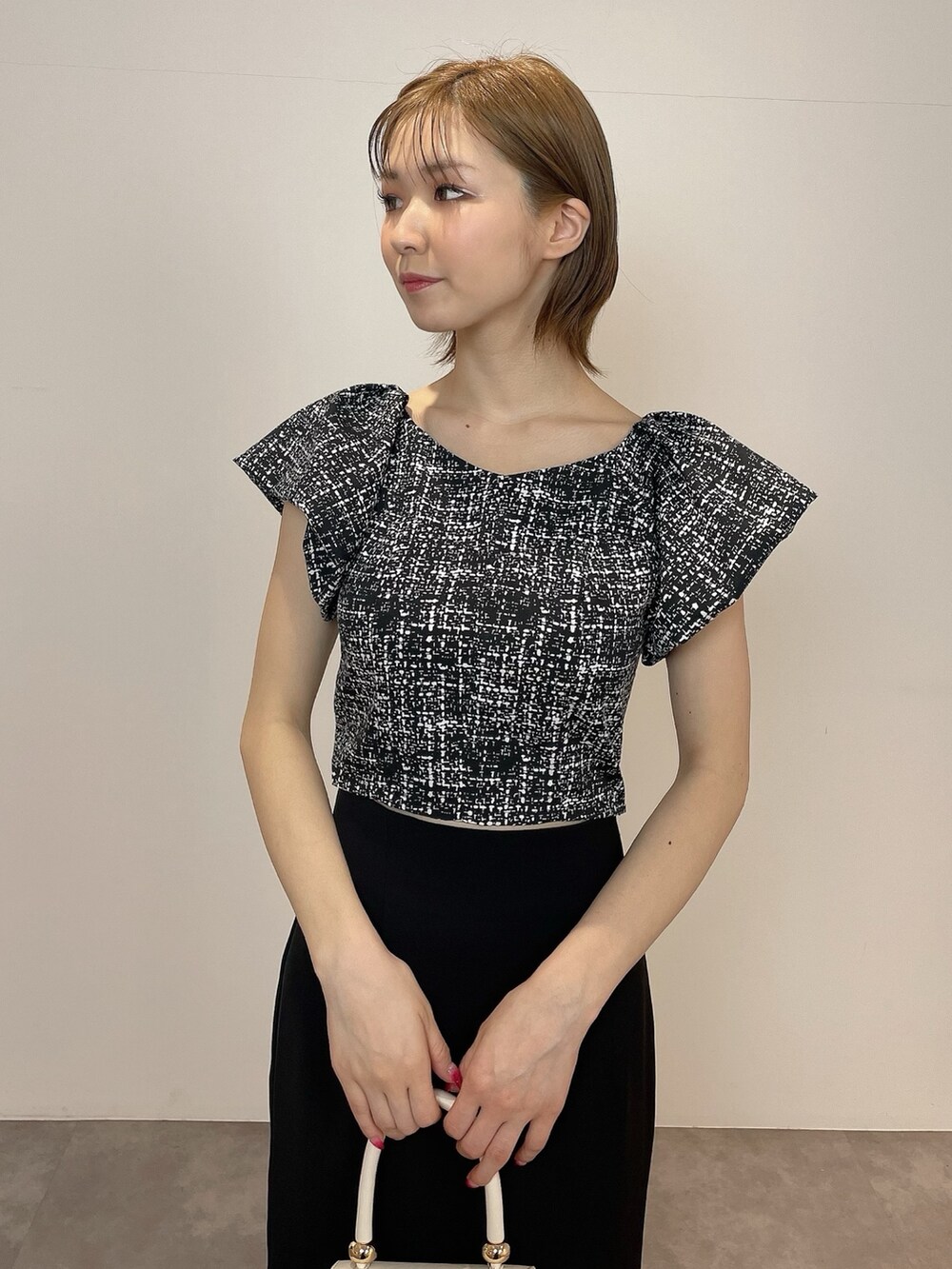 ブラック系のシャツ/ブラウス、ホワイト系のハンドバッグ、ブラック系のパンプスを着用したレディースの春コーディネートの6枚目の写真