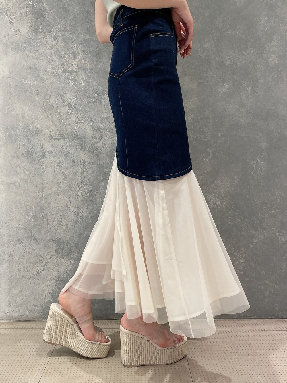 グリーン系のニット/セーター、ブルー系のスカート、ホワイト系のサンダルを着用したレディースの春コーディネートの6枚目の写真