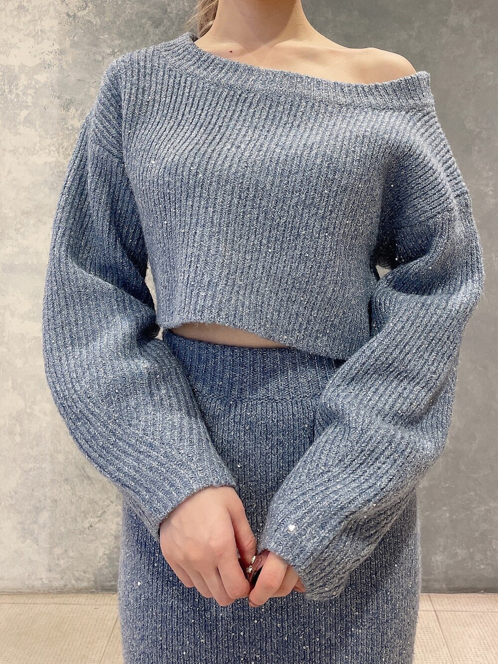 ブルー系のニット/セーター、ブルー系のスカート、ブラック系のブーツを着用したレディースの秋コーディネートの5枚目の写真