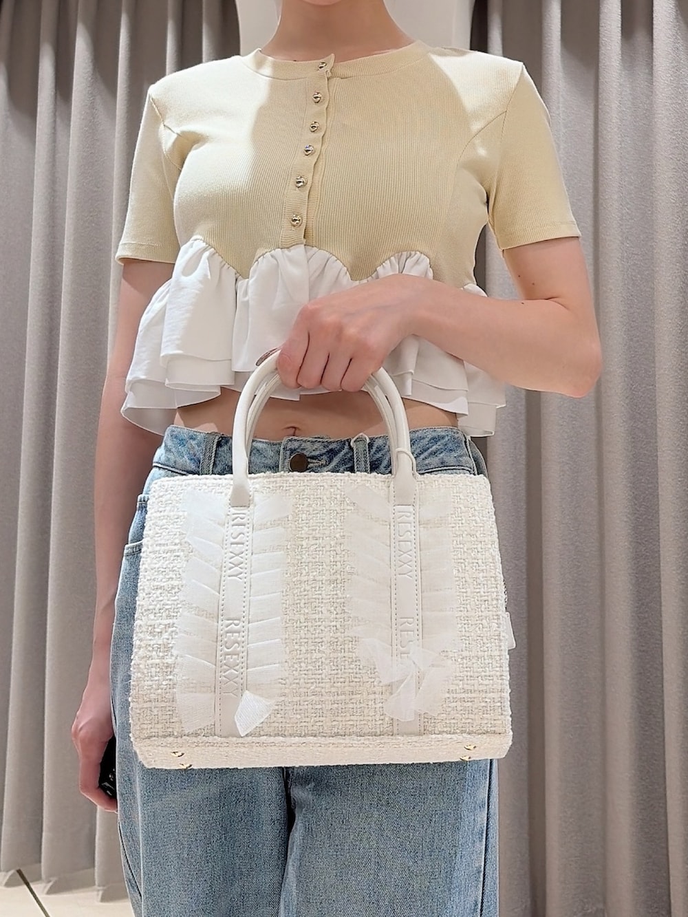 イエロー系のカーディガン/ボレロ、ホワイト系のトートバッグ、ブルー系のデニムパンツを着用したレディースの夏コーディネートの5枚目の写真